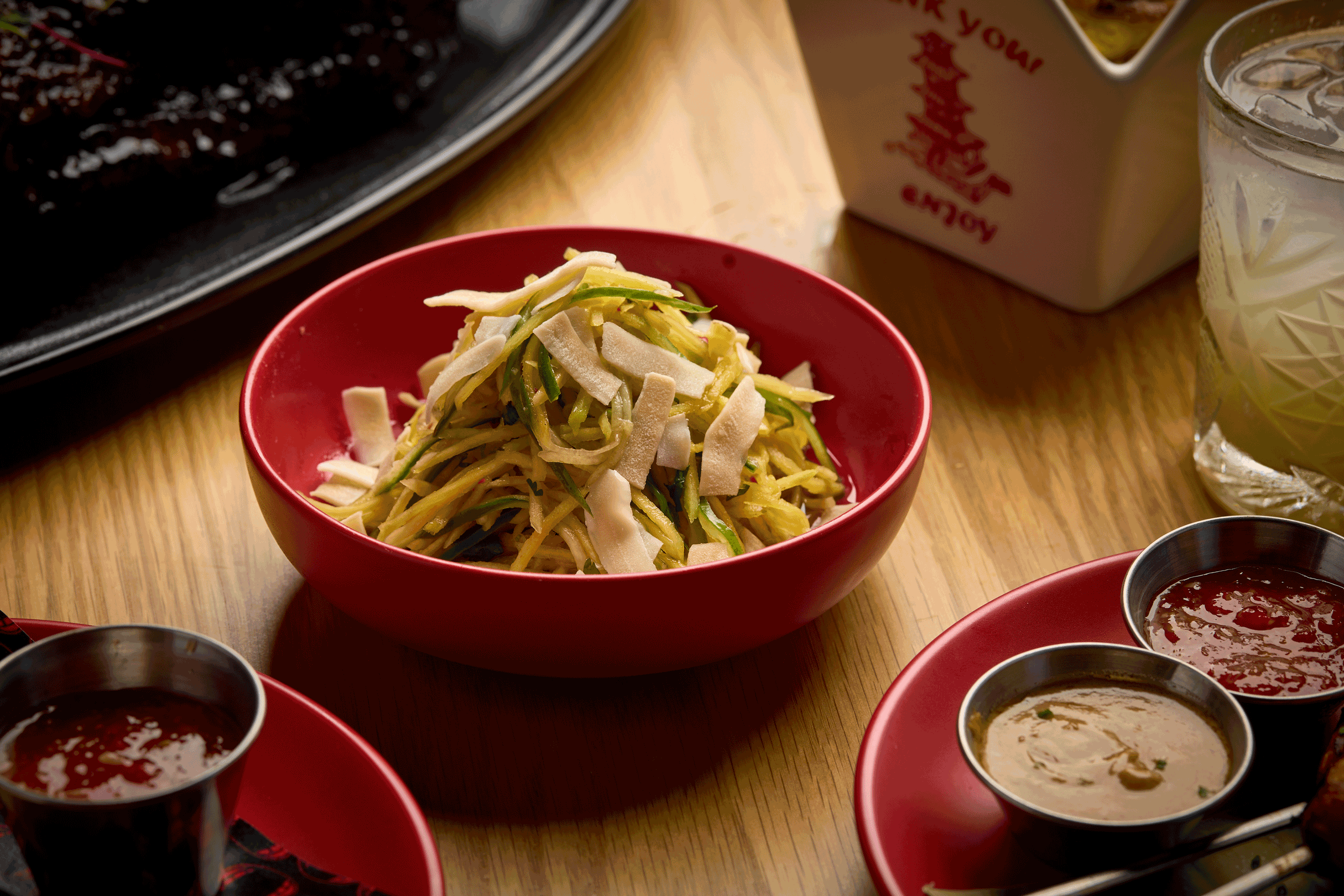 a bowl of noodles and sauces on a table