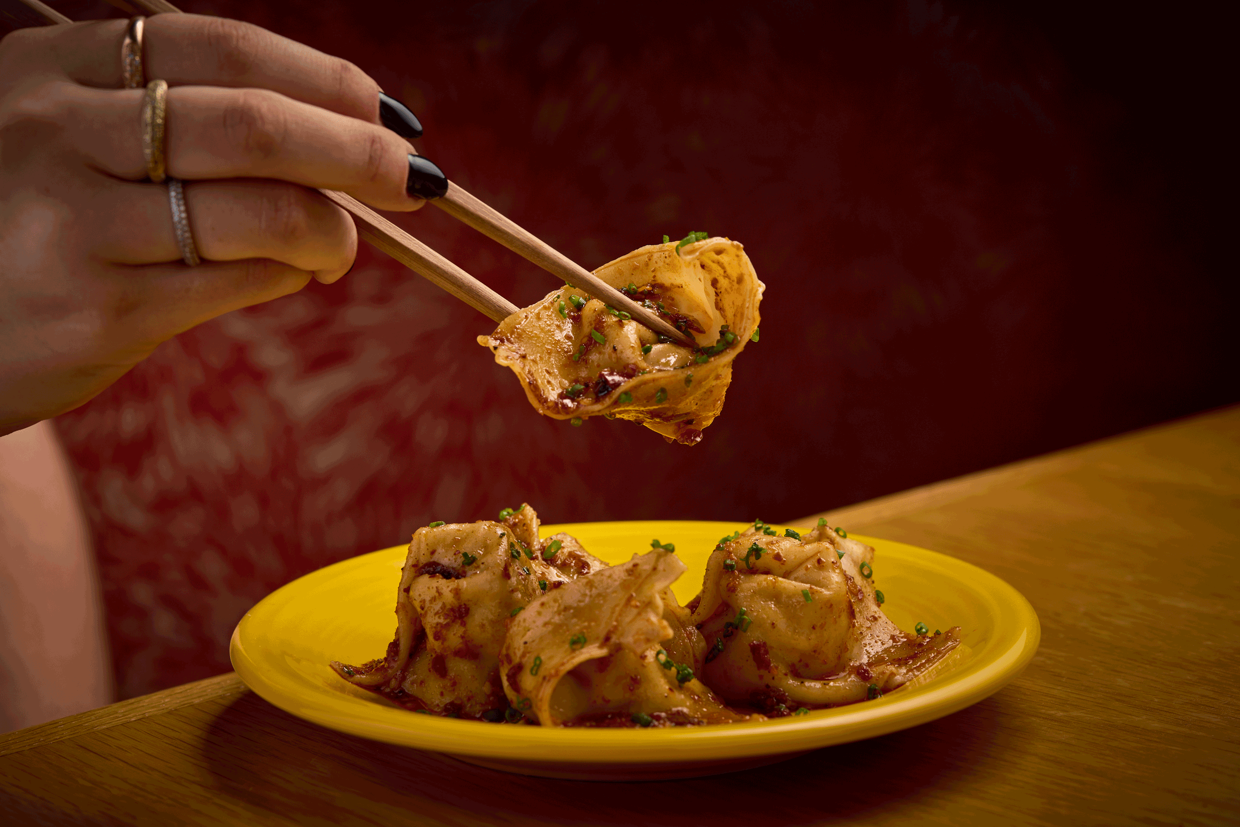 a person holding chopsticks over food on a plate