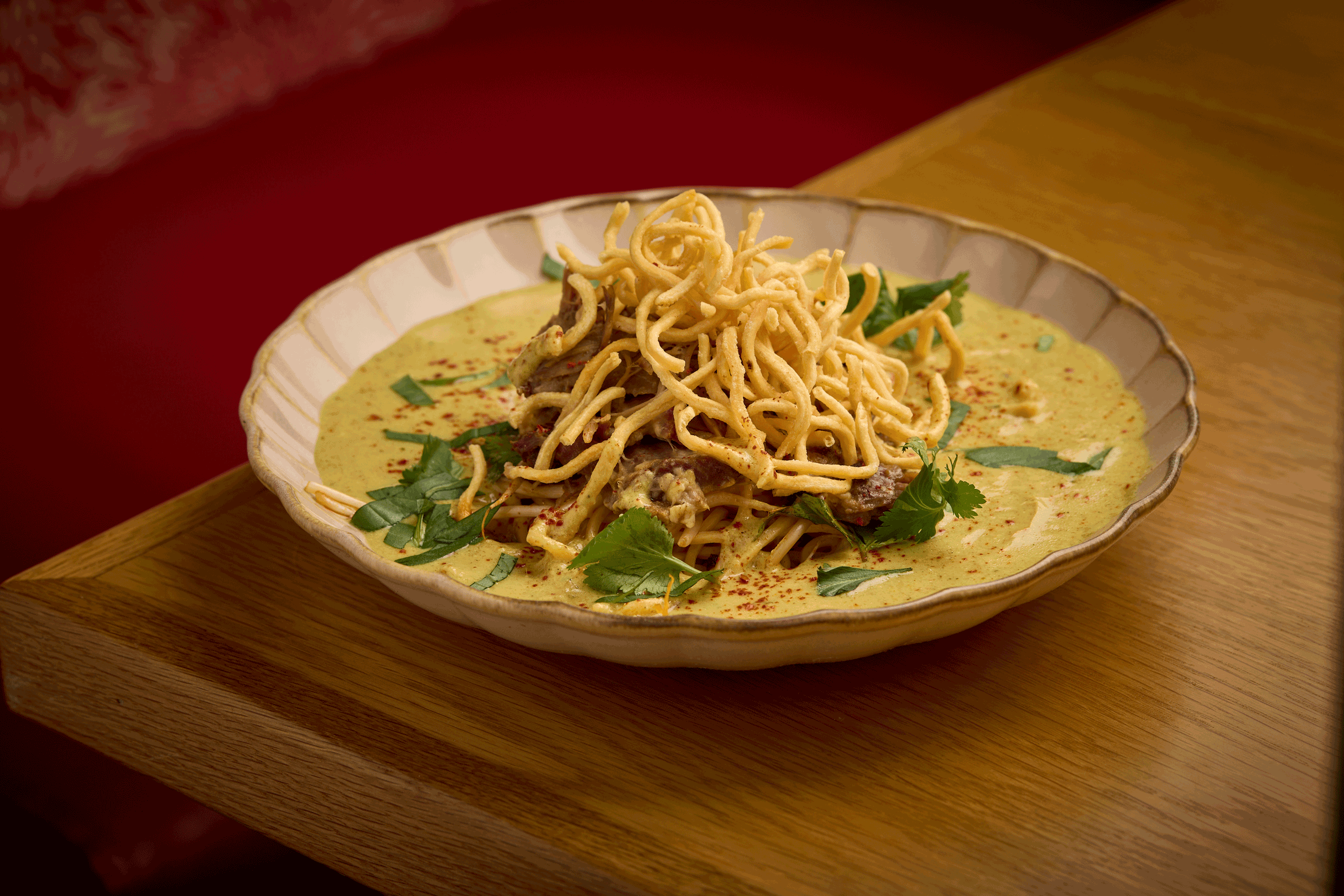 a bowl of noodles and greens on a table