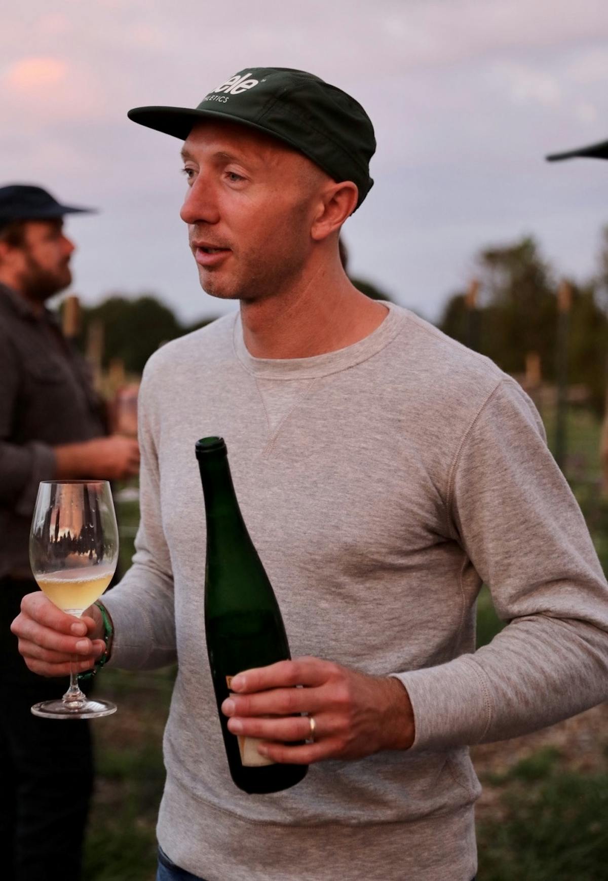 a man in a ciele hat holding a bottle of wine