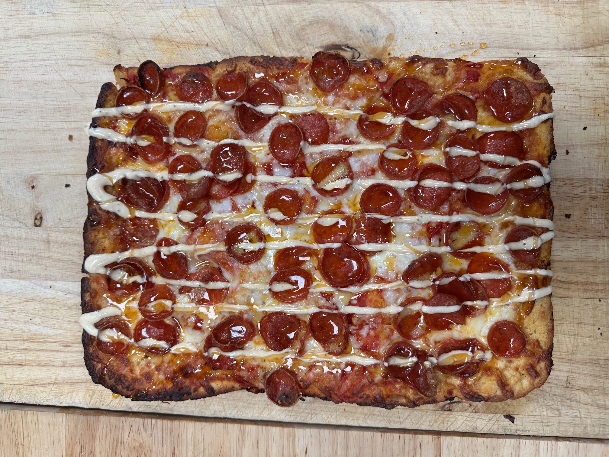 a pepperoni pizza sitting on top of a wooden cutting board