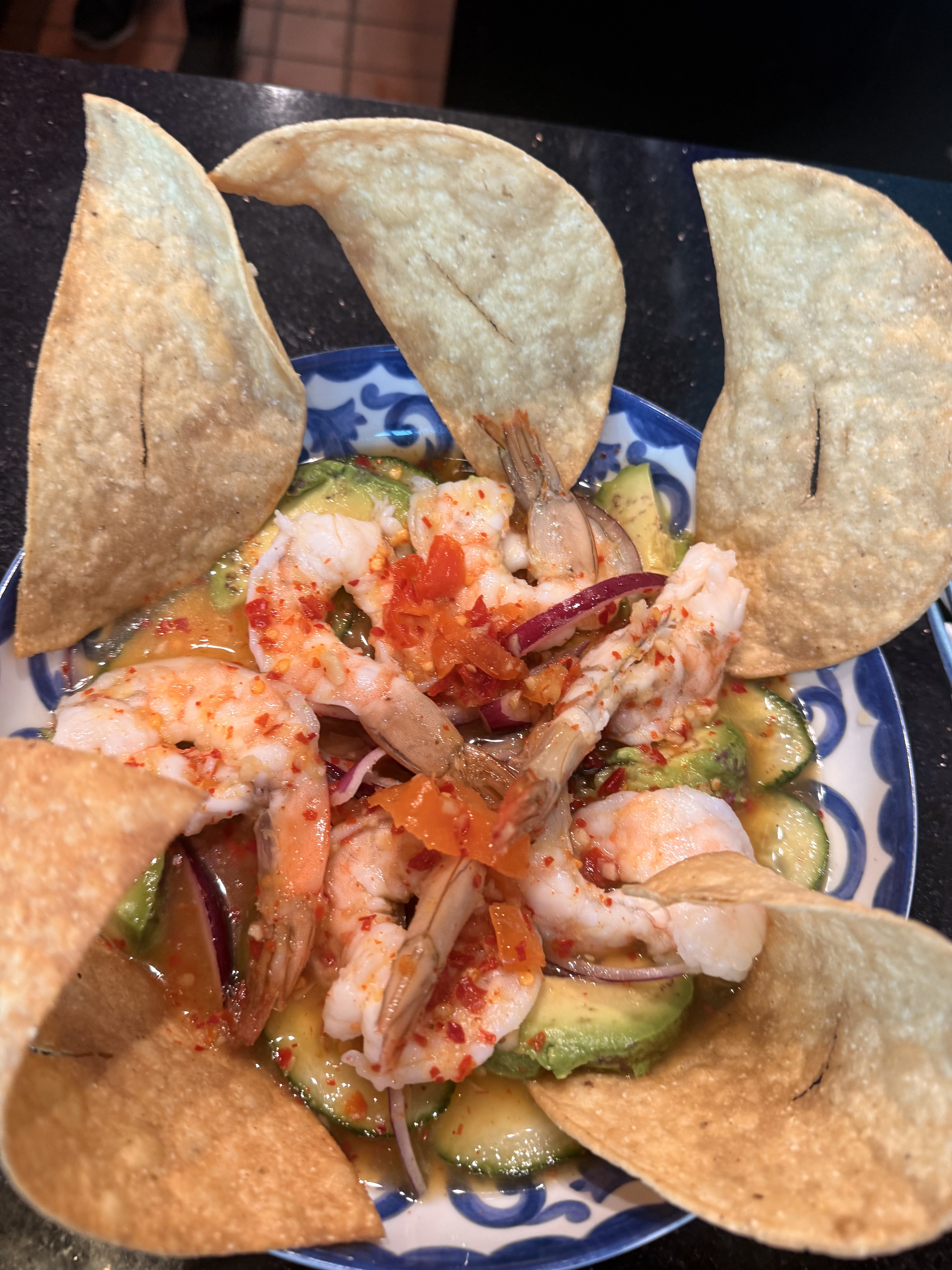 a plate of shrimp and avocado salad with chips