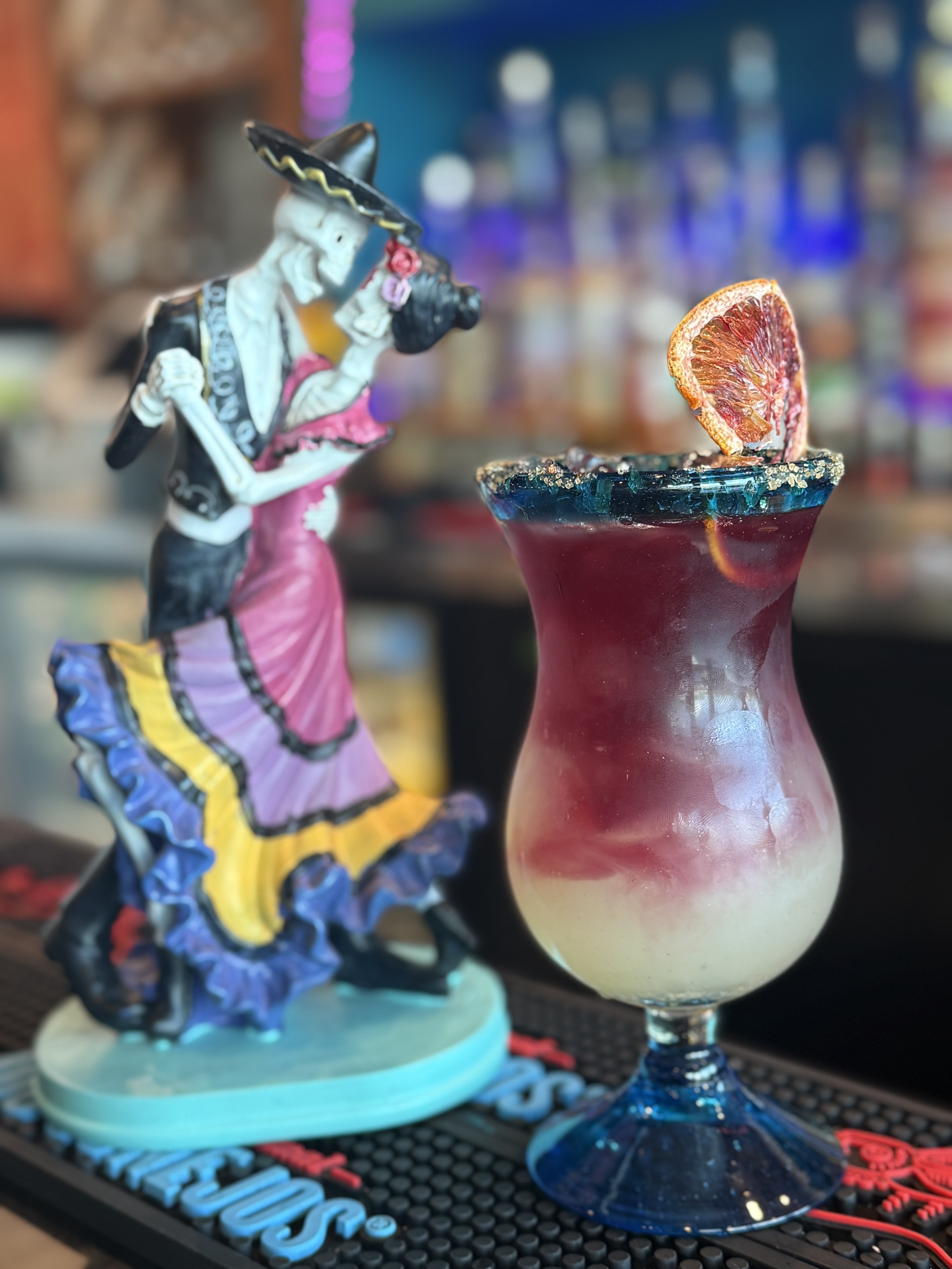 a glass with a drink and a statue of a skeleton