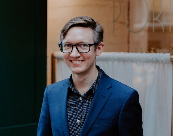 a man wearing glasses and smiling at the camera