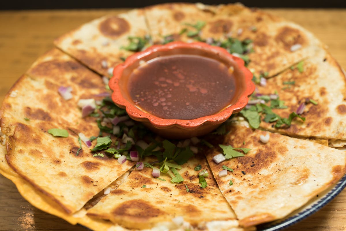 a plate of quesadilla with dipping sauce