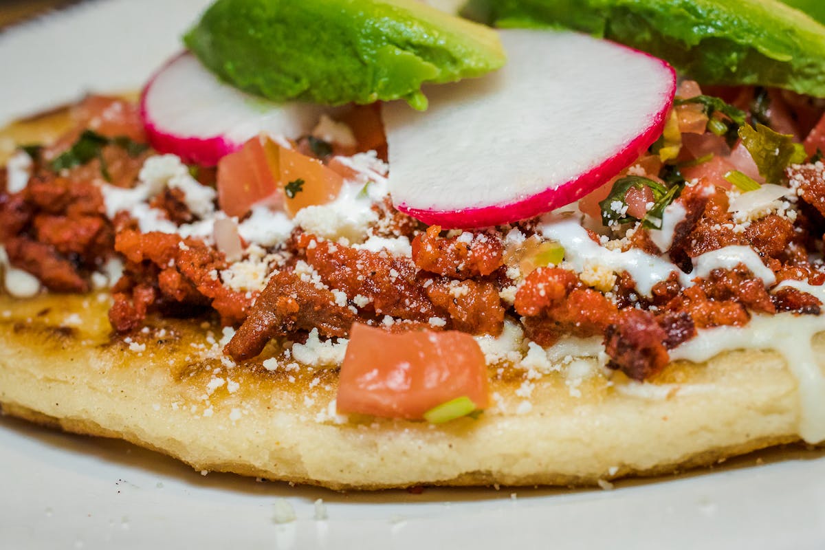 a close up of a taco or tostada with meat and veggies
