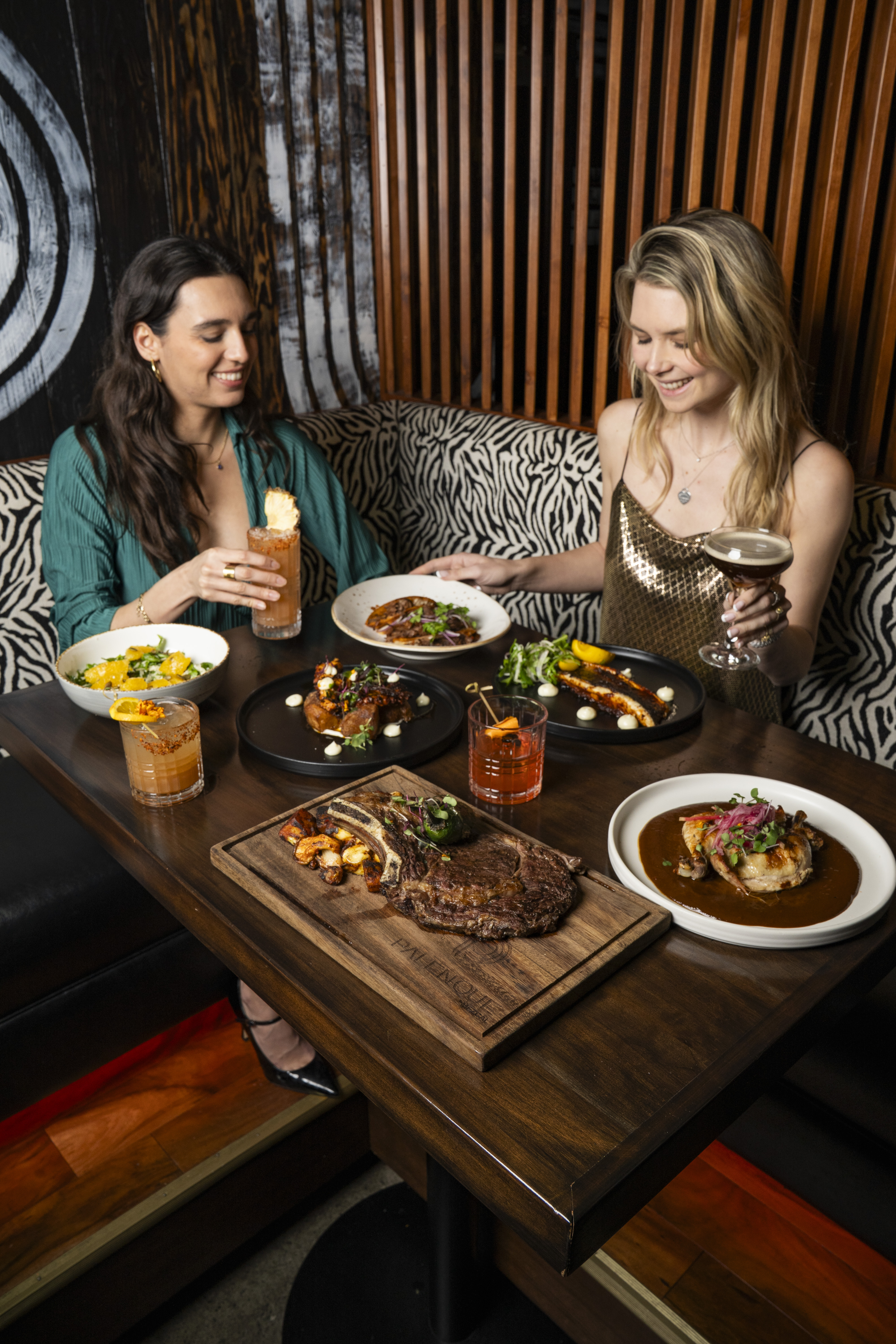 two women sitting at a table with food