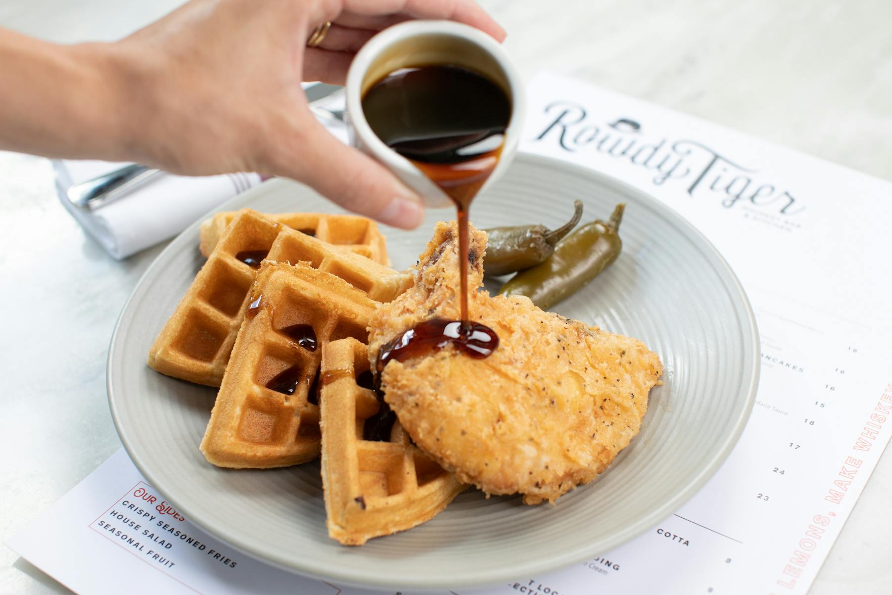 a person pouring honey on some waffles