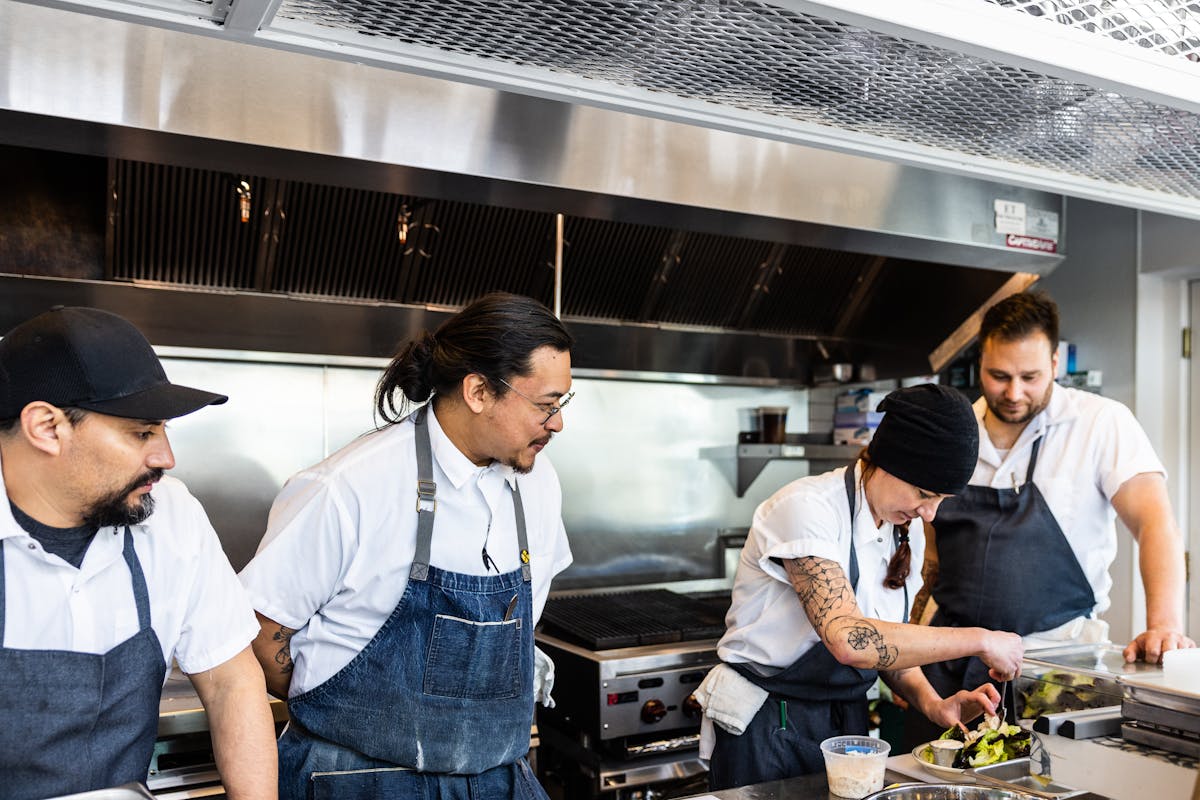 a group of people standing in a kitchen preparing food