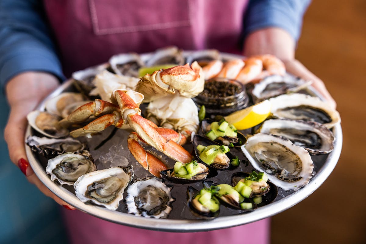 a person holding a tray with fresh seafood