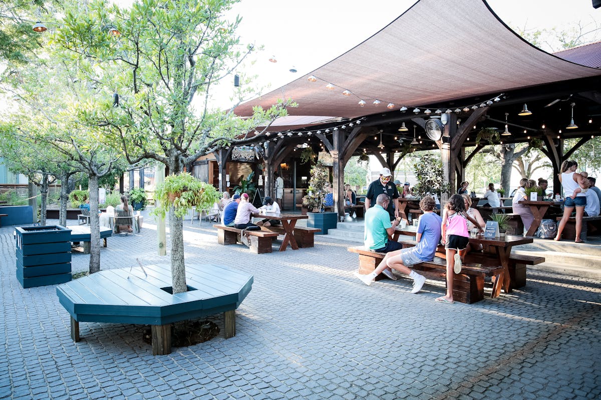 a group of people sitting at a table with a blue umbrella