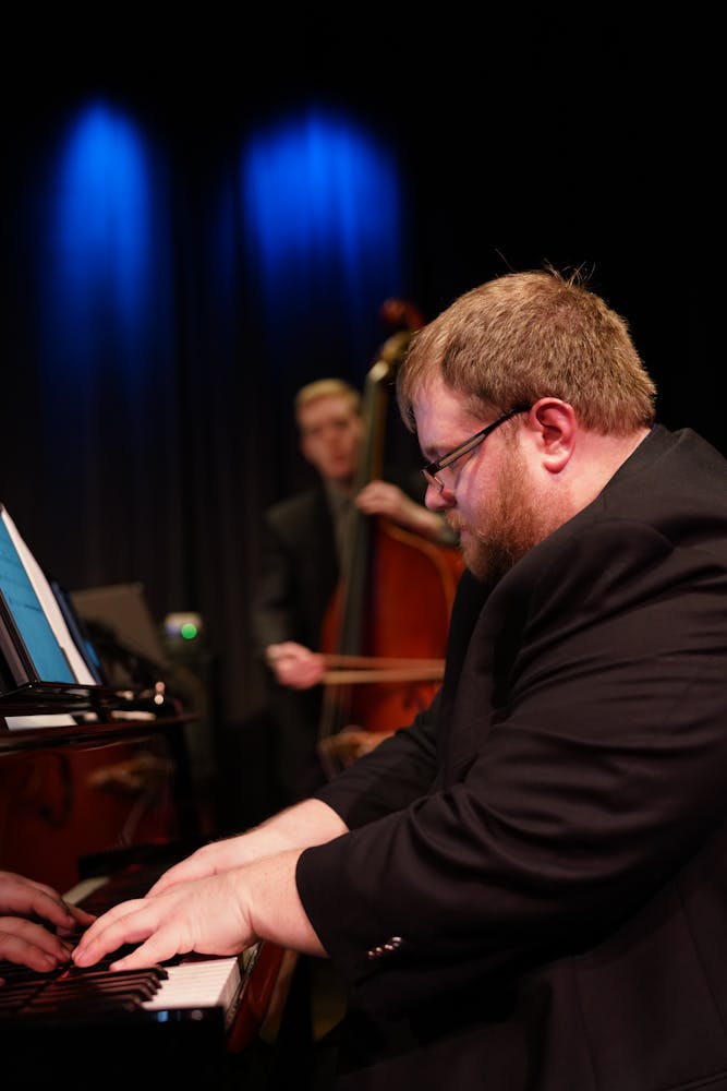 a man using a laptop computer sitting on top of a piano