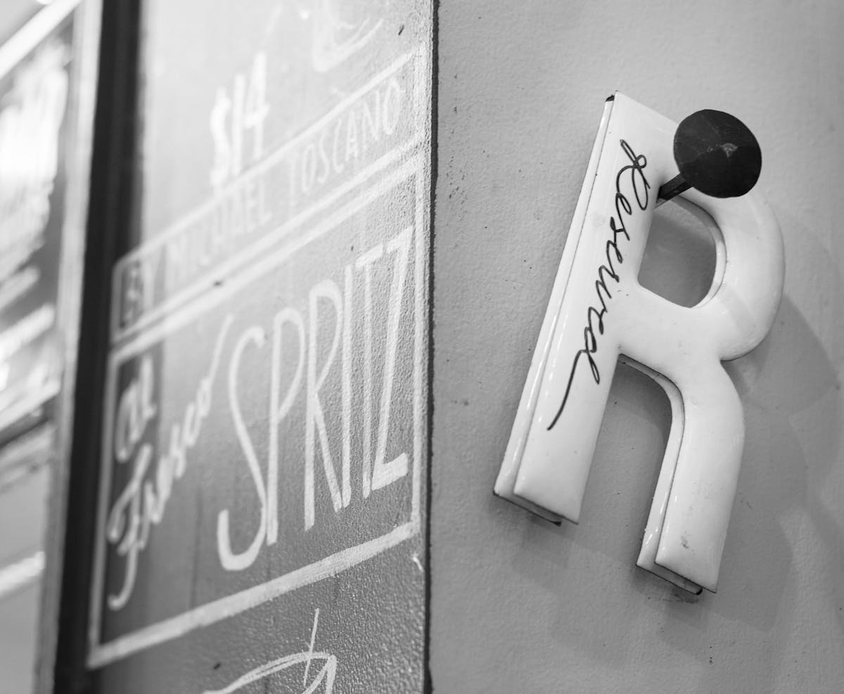 a black sign with white text hanging from the side of a building