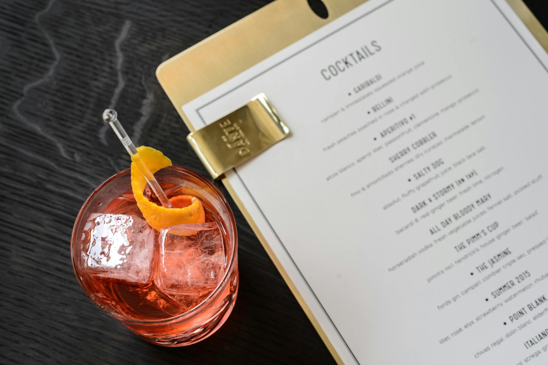 a menu an a cocktail on a table