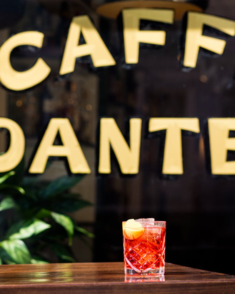 a black sign DANTE with a glass of Negroni