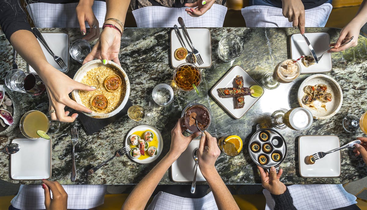 two people sitting on a table topped with food