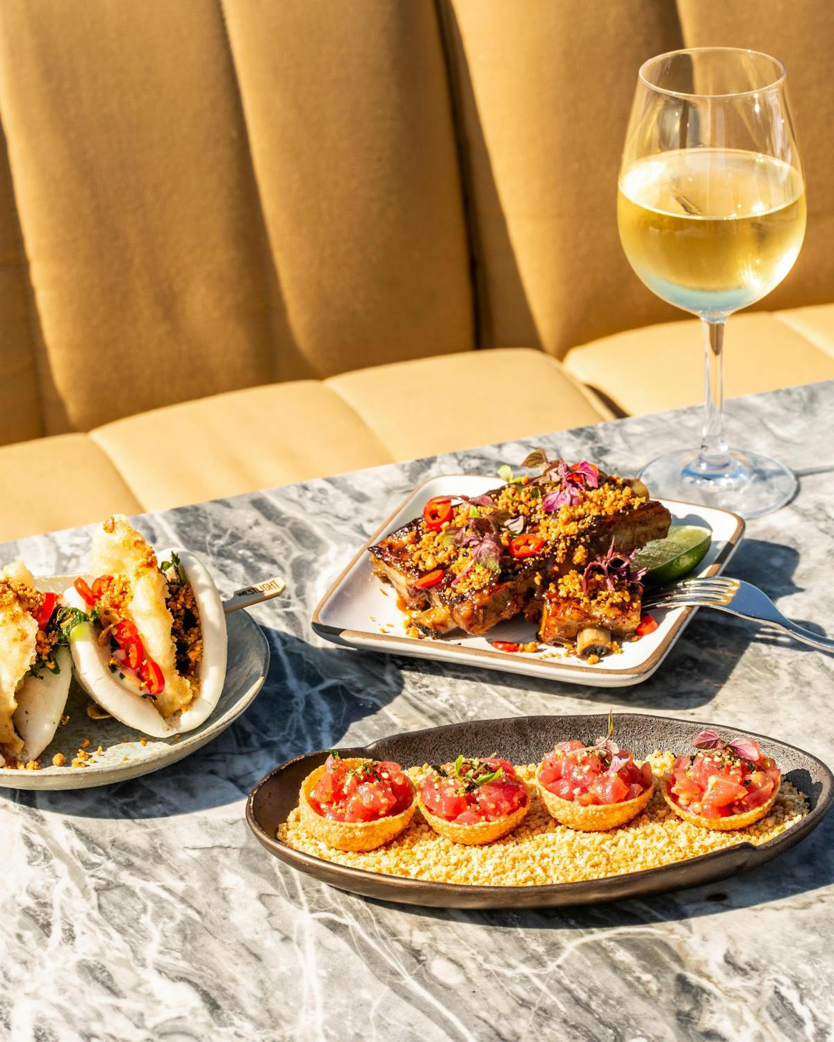 three plates of food and a cocktail on a dining table