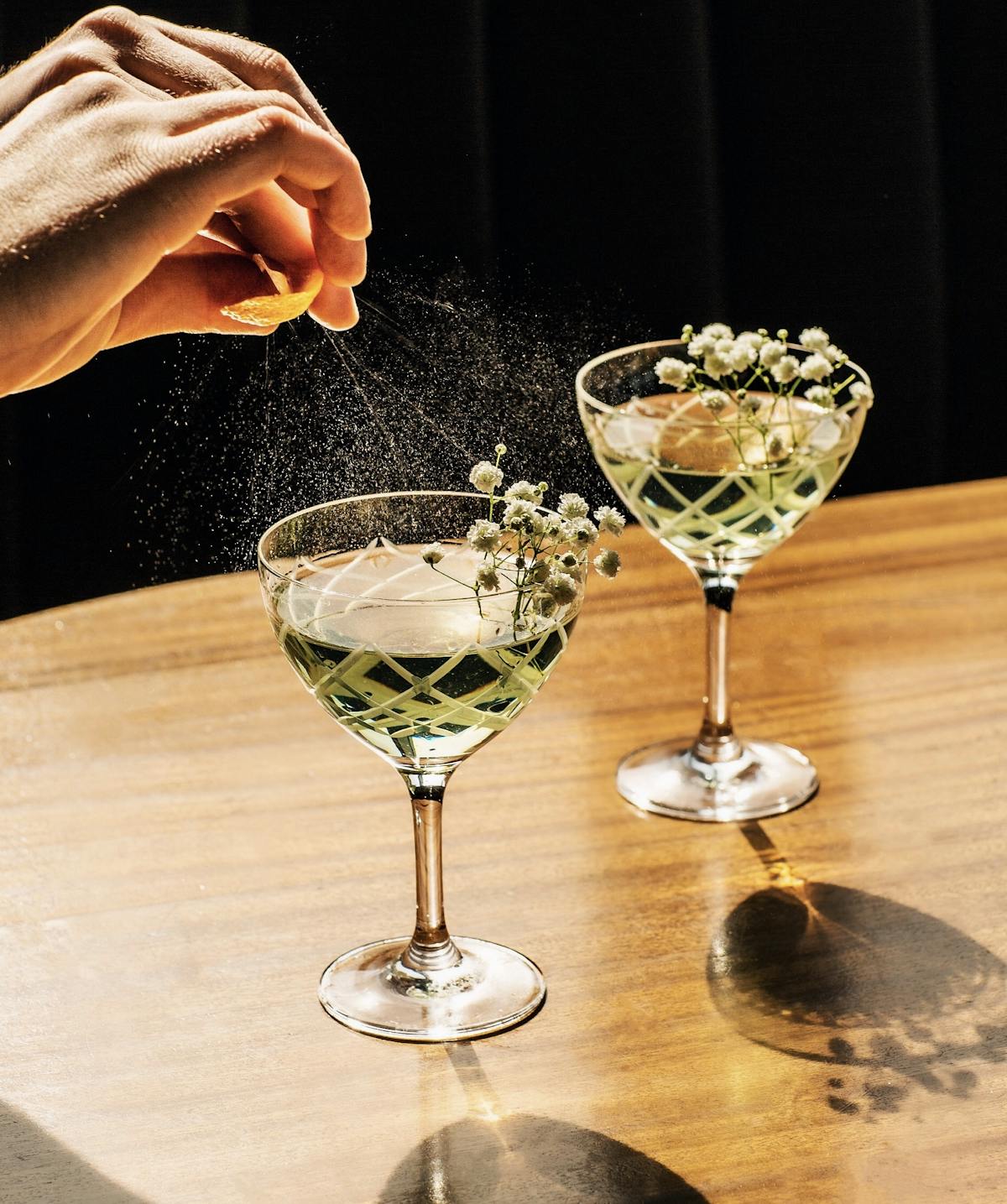 a person pouring lemon to two cocktails