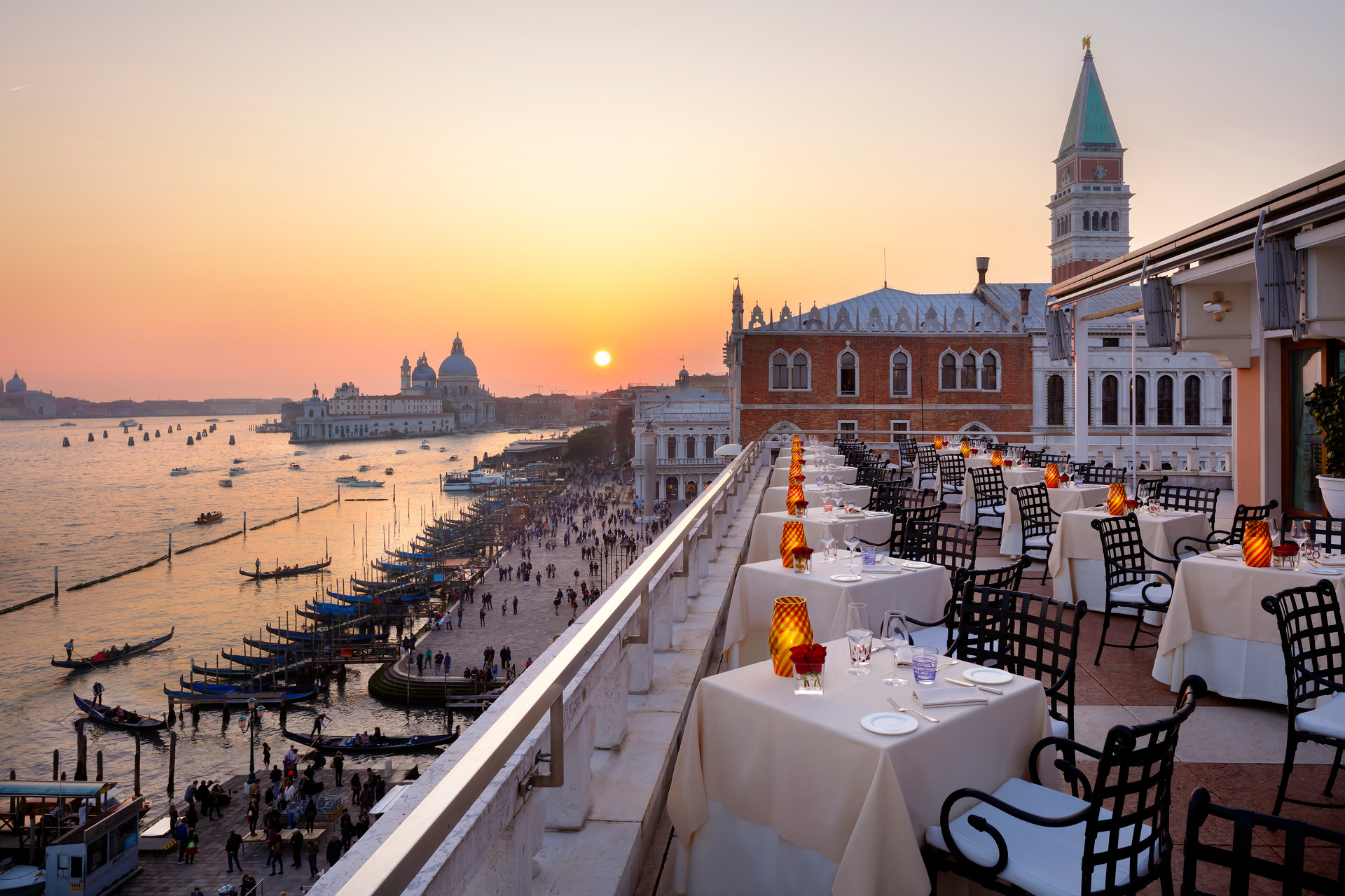 a rooftop restaurant with tables and chairs on a balcony overlooking a body of water