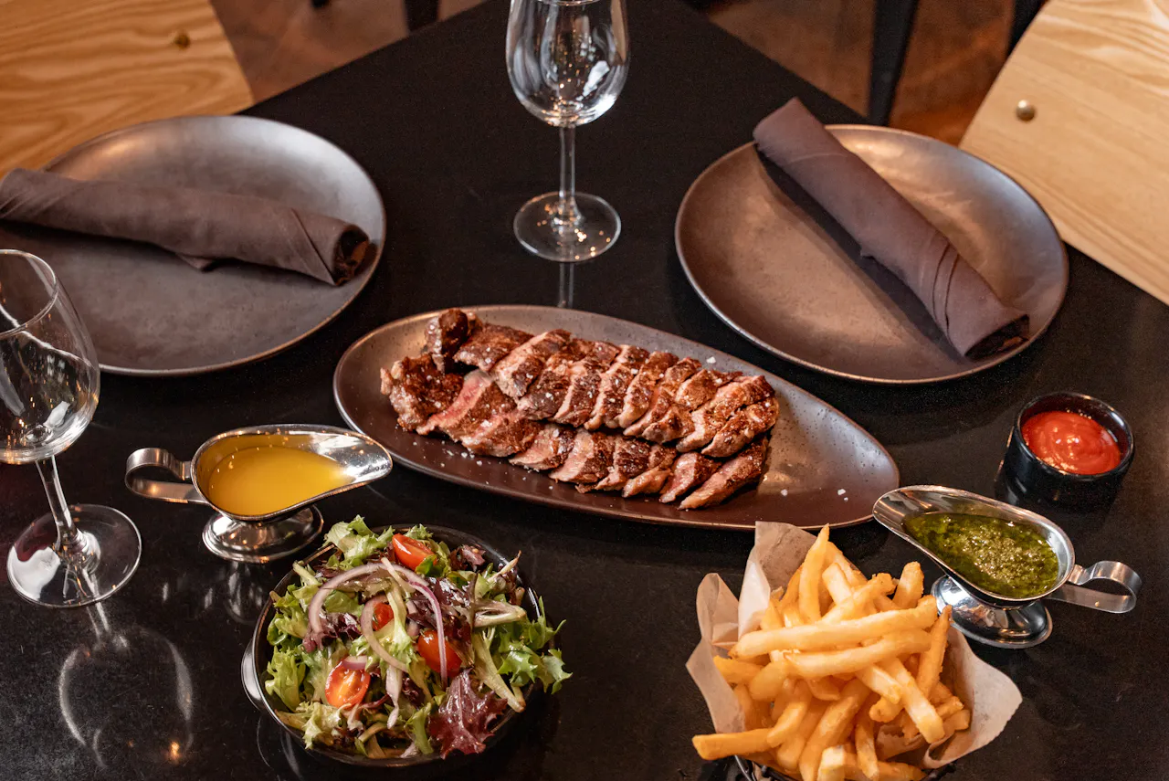 Sliced American Wagyu on a board with battered fries, Goma salad and sauces
