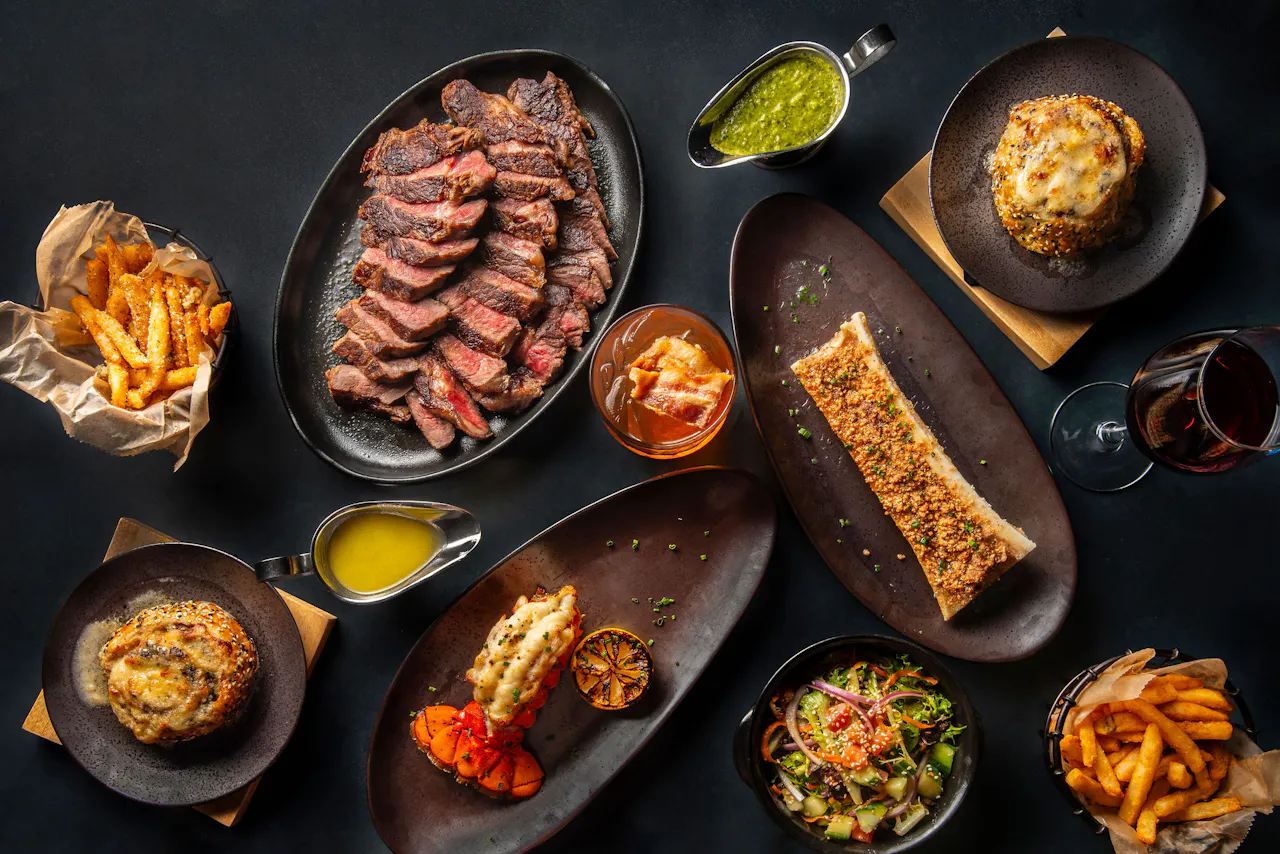 Overhead spread of sliced American Wagyu, fries, salad and sides