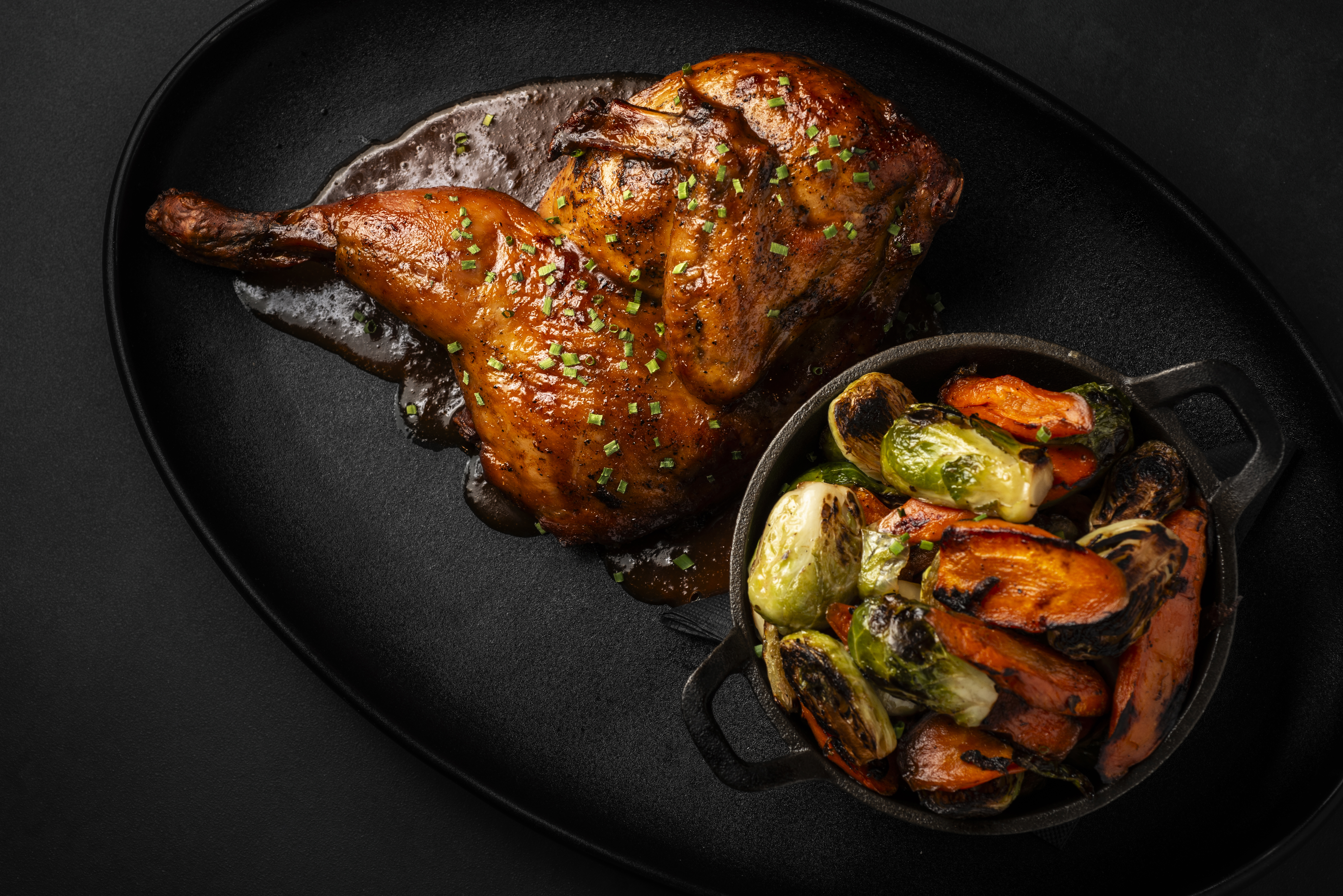 a chicken and vegetables on a black plate