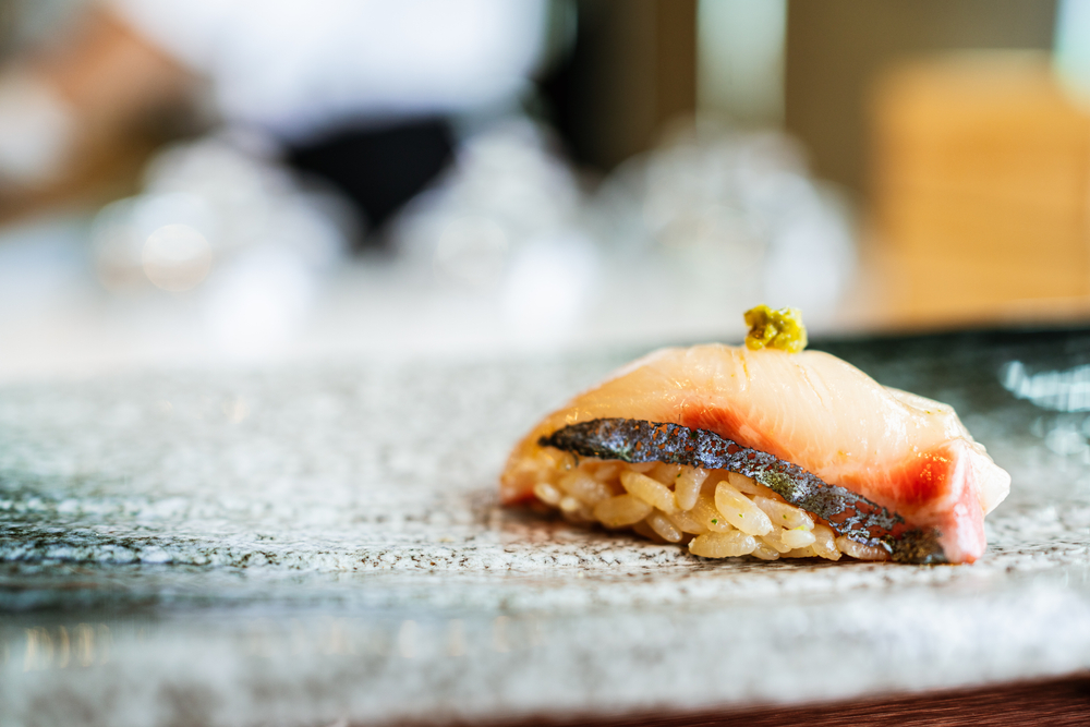 Shima Aji Striped Jack nigiri close up on plate with wasabi on top