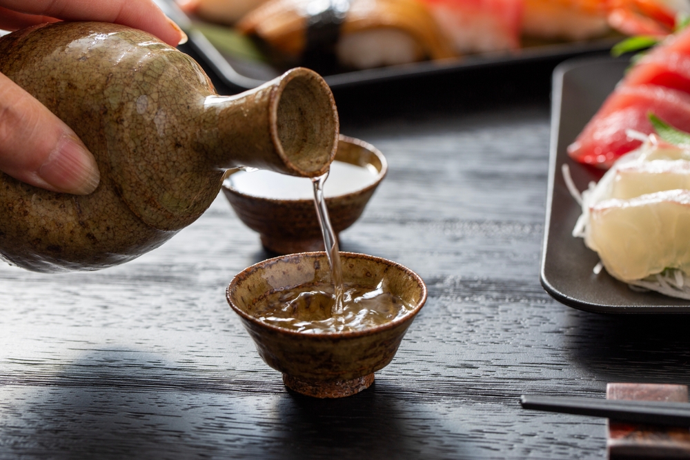 Pouring sake next to sushi