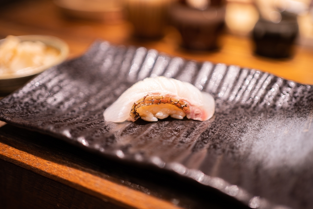 Madai sushi placed on black dish in sushi restaurant