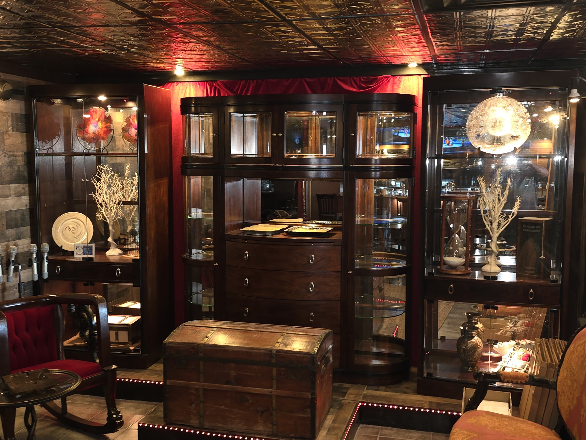 A spacious room filled with various furniture pieces and abundant glass elements, creating a bright and airy atmosphere