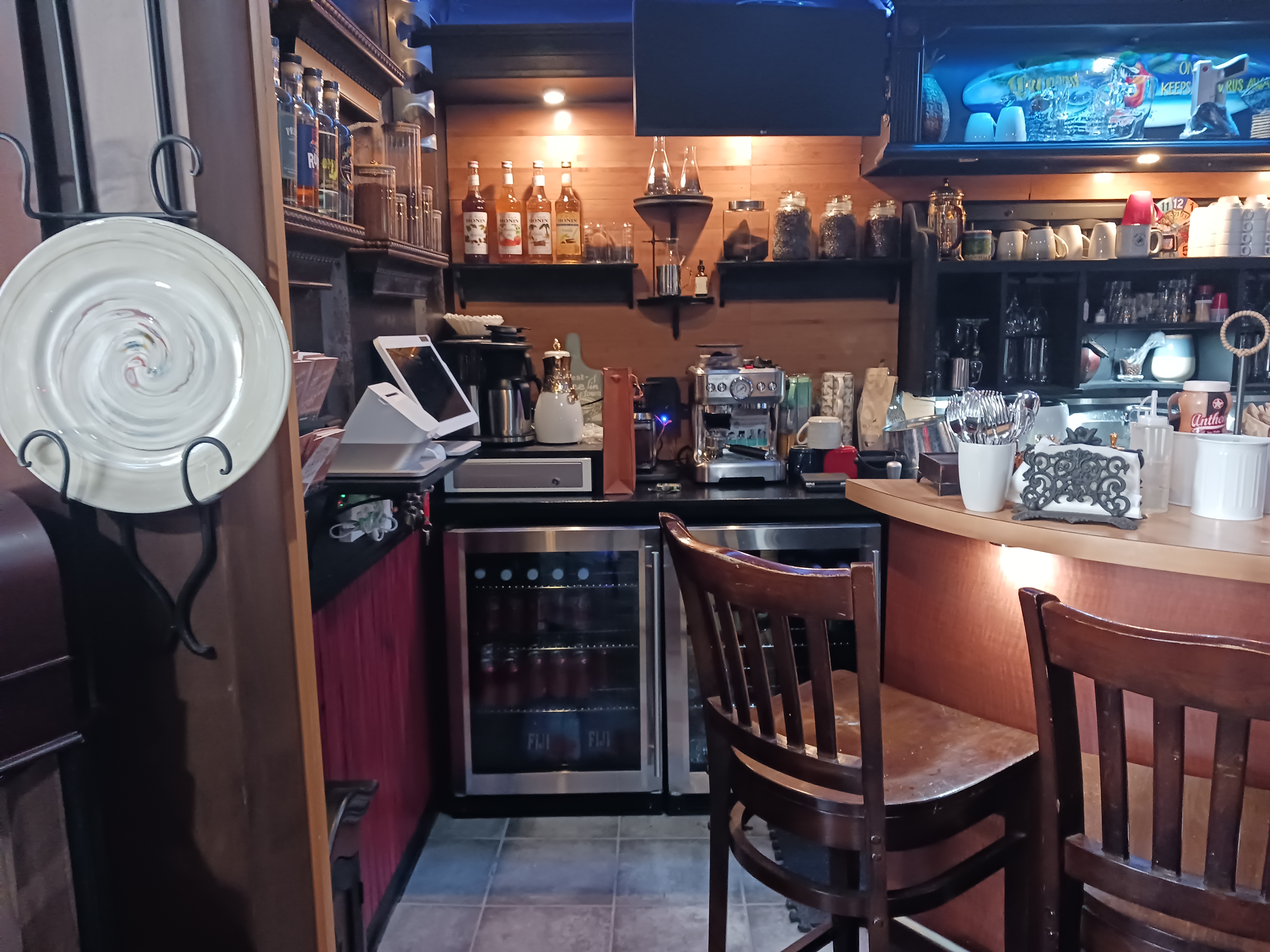  A spacious bar featuring a large counter with several chairs arranged around it for patrons to sit and enjoy drinks