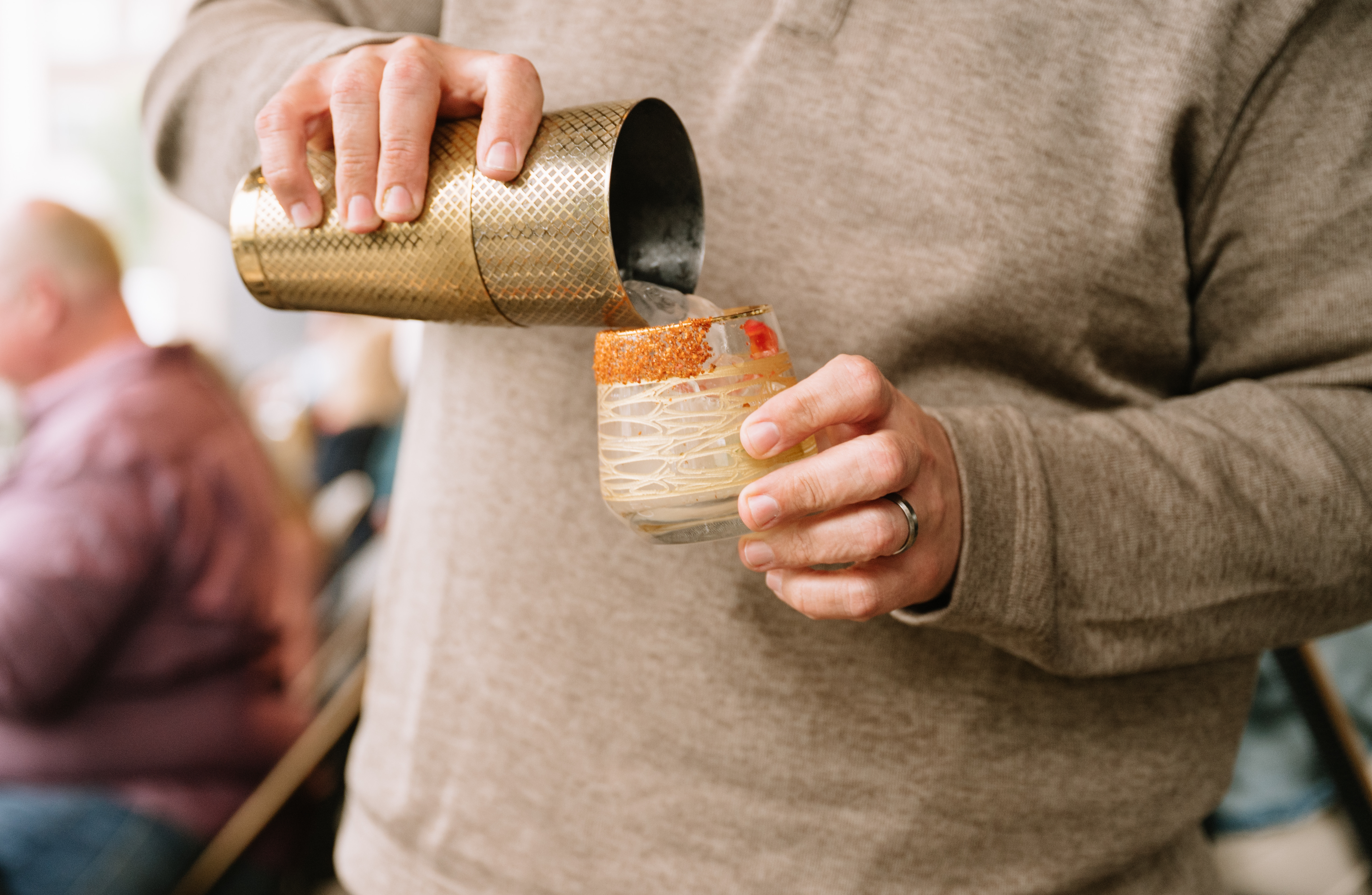 a person pouring a drink into a glass