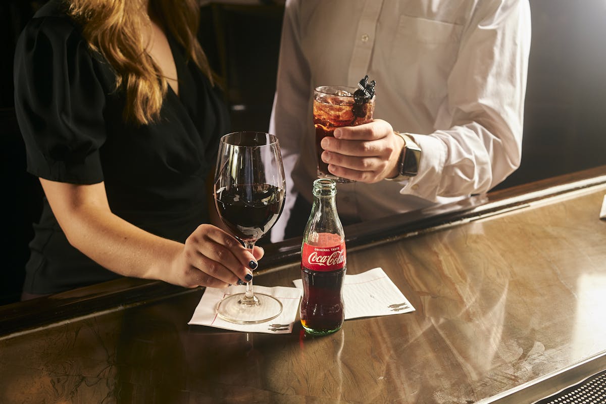 Woman with a glass of red wine and man with an Elmo Cola