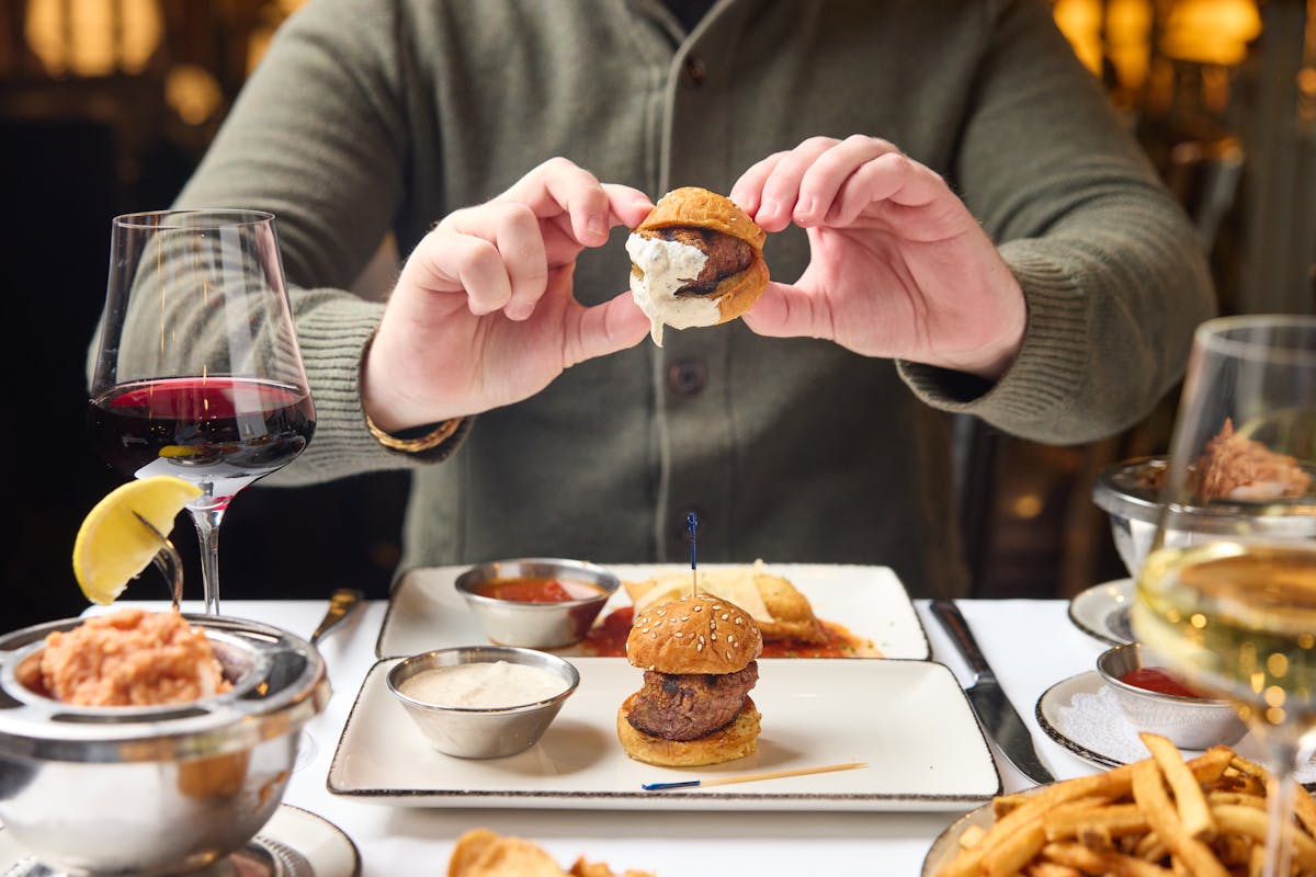 Man holding filet slider dipped in creamy horseradish