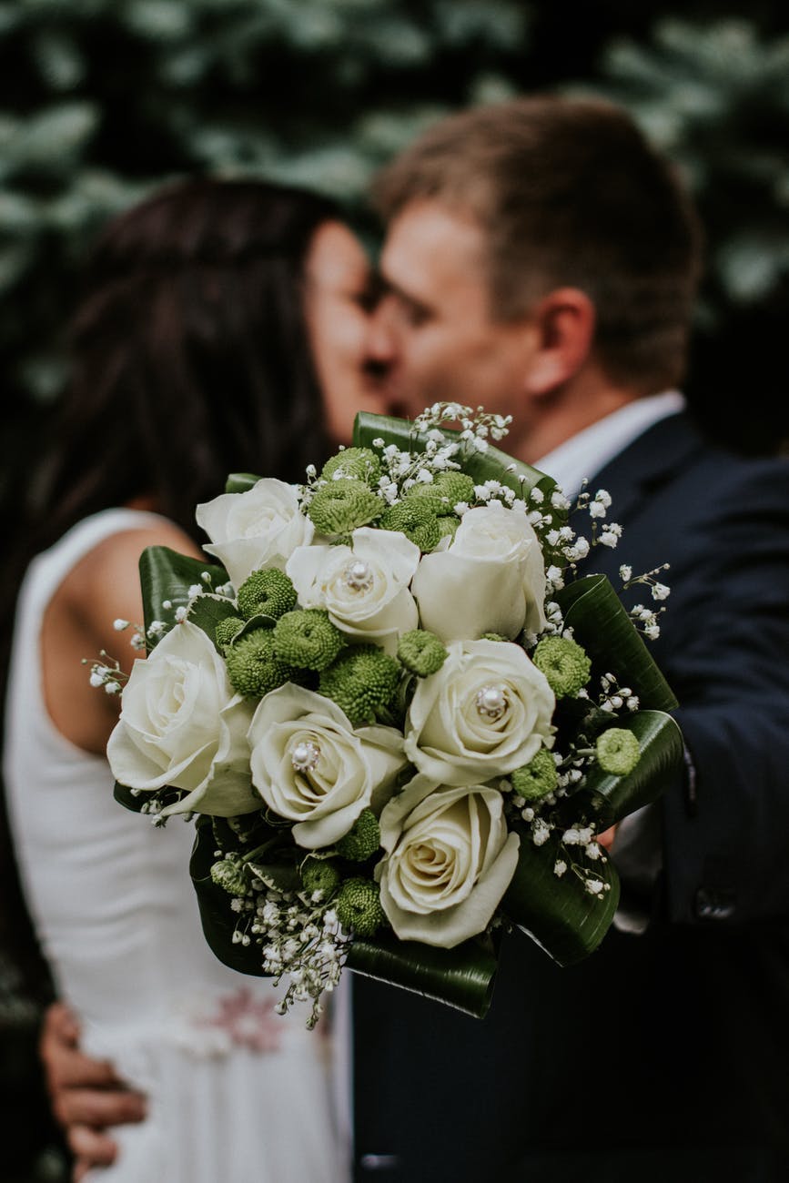 a bouquet of flowers with a couple kissing on the background