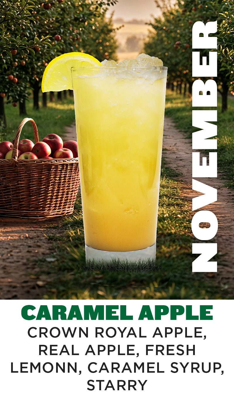 a glass of yellow liquid with a basket of apples in the background