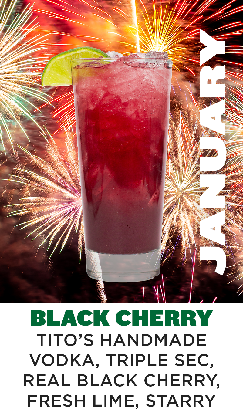 a glass with a drink and fireworks in the background