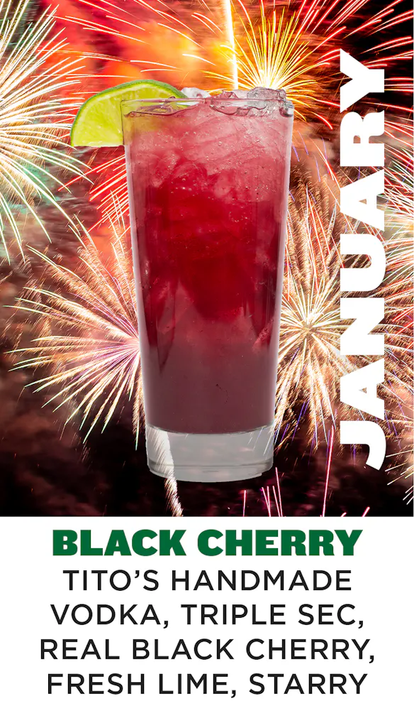 a glass with a drink and fireworks in the background