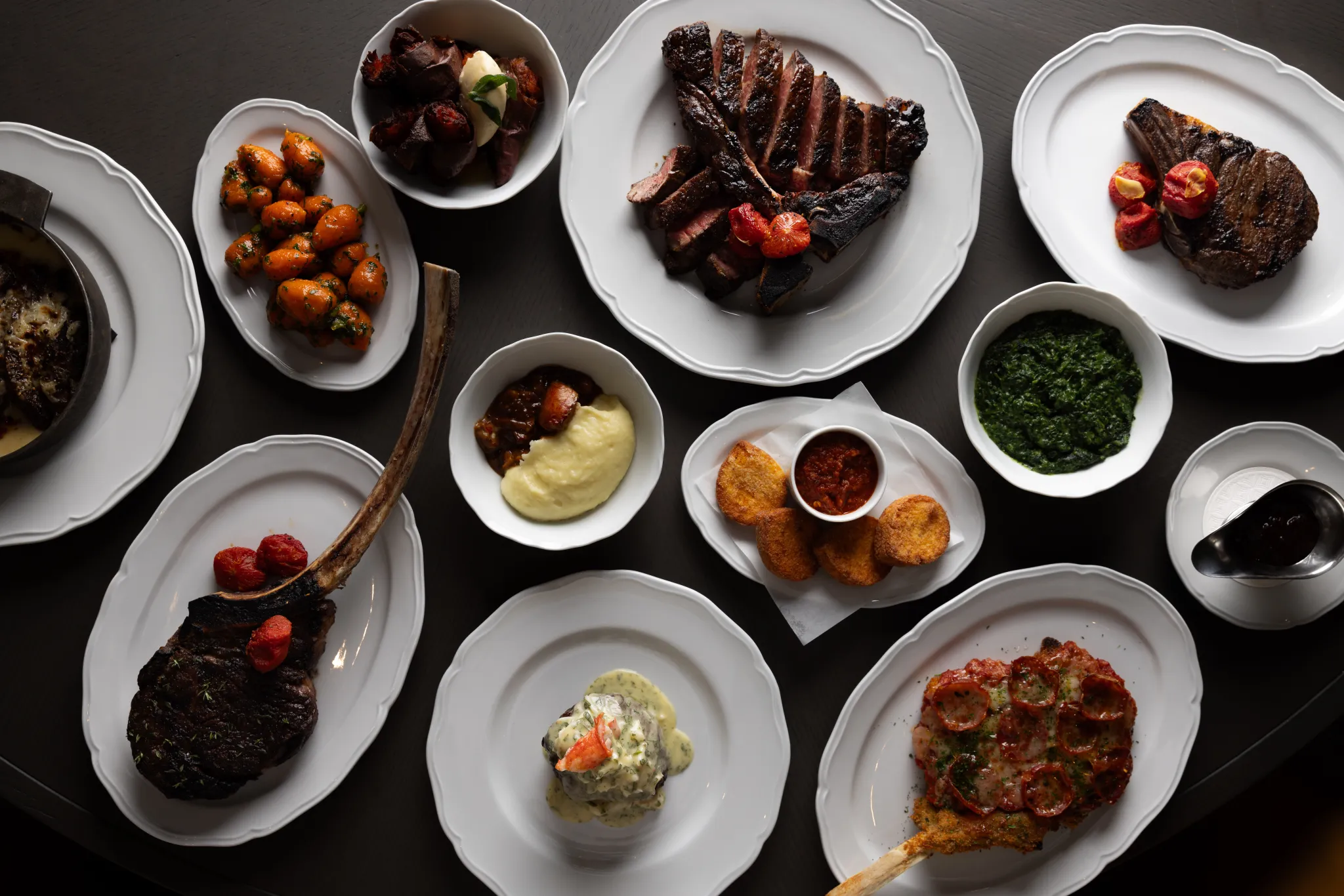 Assorted steak cuts, sauces, and sides arranged on a dining table before pairing wine with steak.