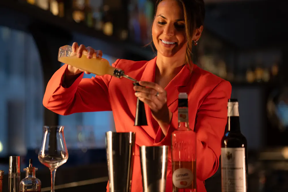 a woman pouring a drink into a shaker