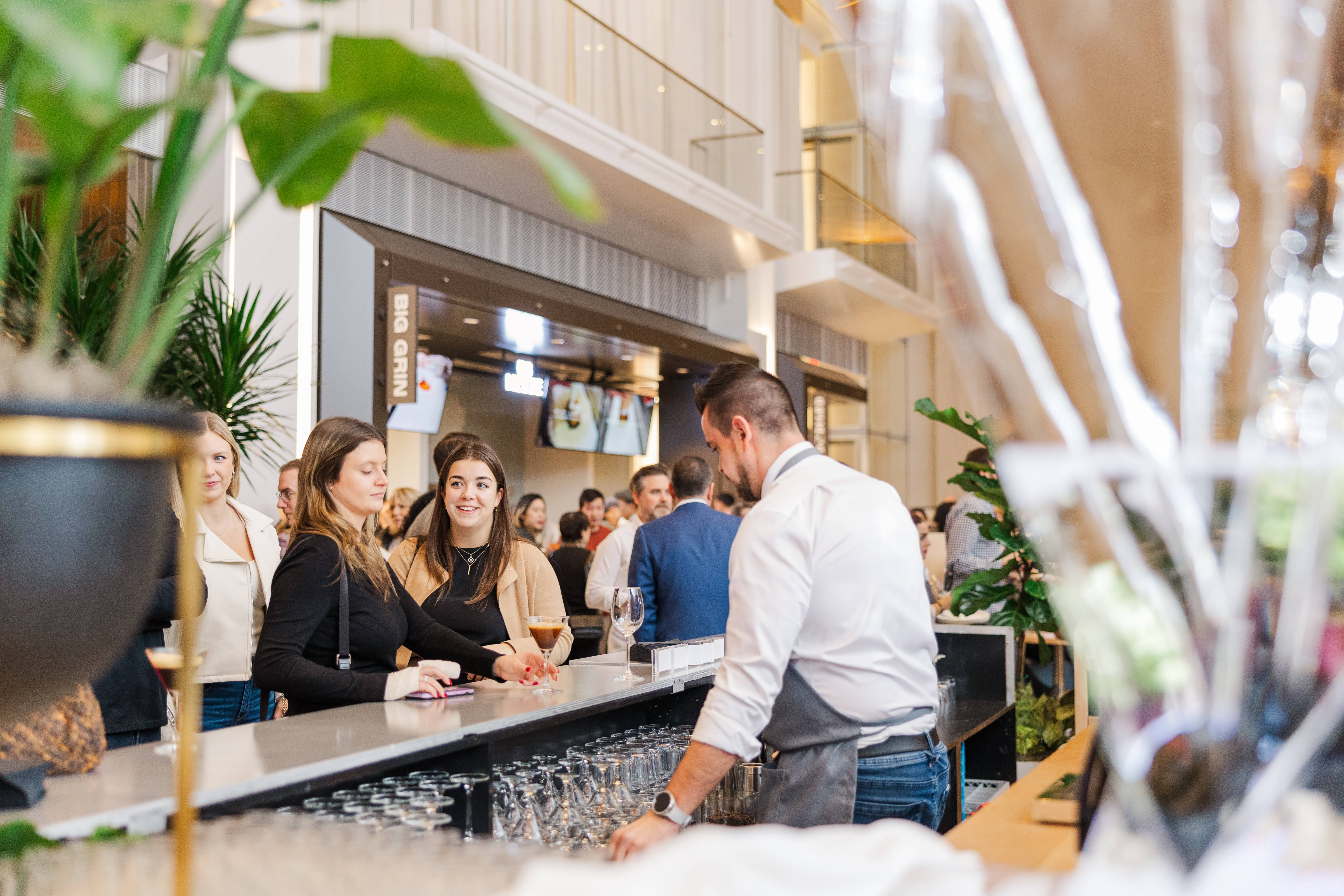 Bartender serving cocktails to a busy crowd at a bright indoor food hall called The Lineup, one of Boston’s hidden gems.