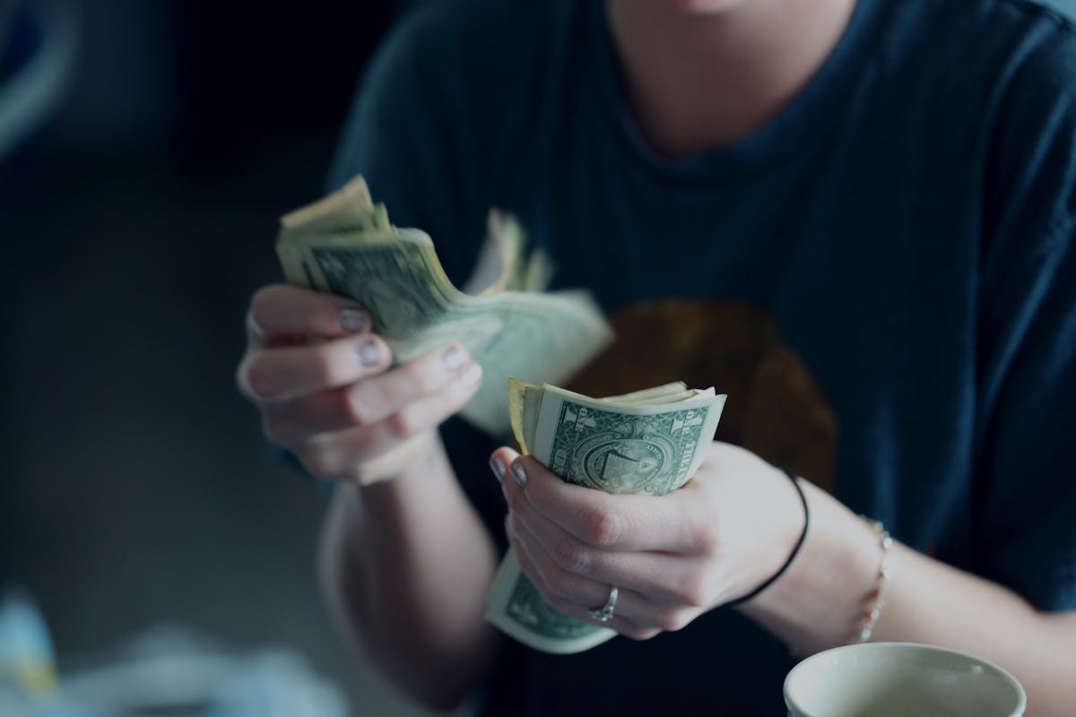 a person sitting at a table with a cup of coffee and money