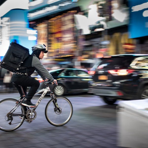 a person riding a bicycle on a city street - delivery
