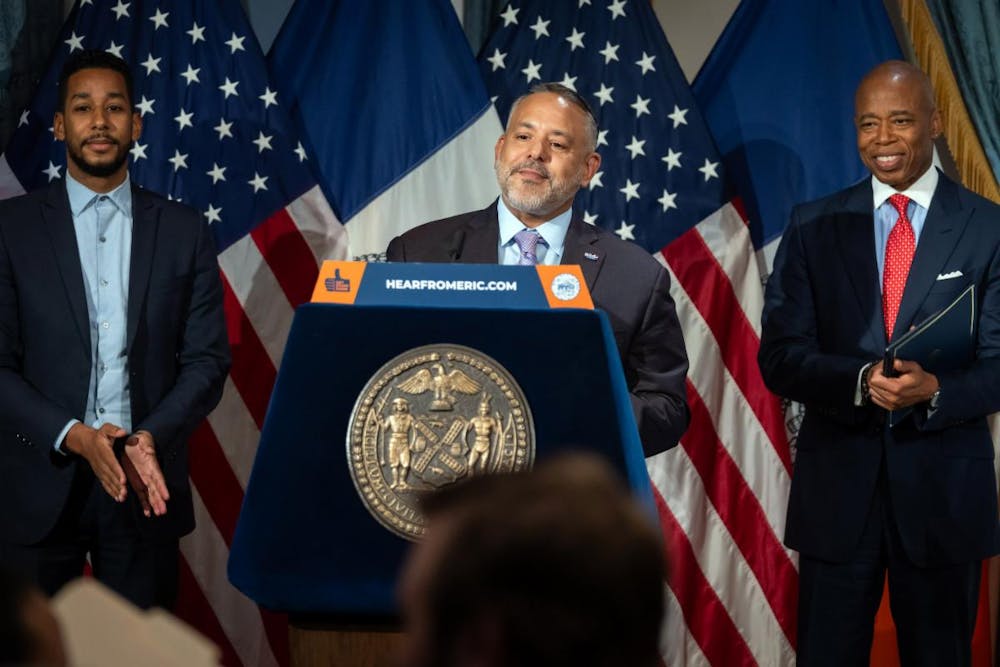 Eric Adams et al. standing next to a man in a suit and tie