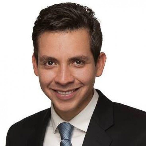 a man wearing a suit and tie smiling at the camera