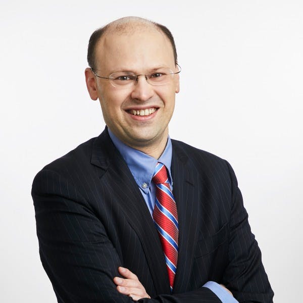 a man wearing a suit and tie smiling at the camera