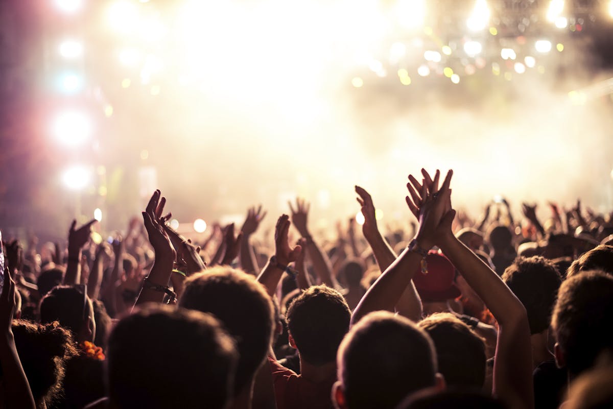 a group of people watching a band on stage in front of a crowd