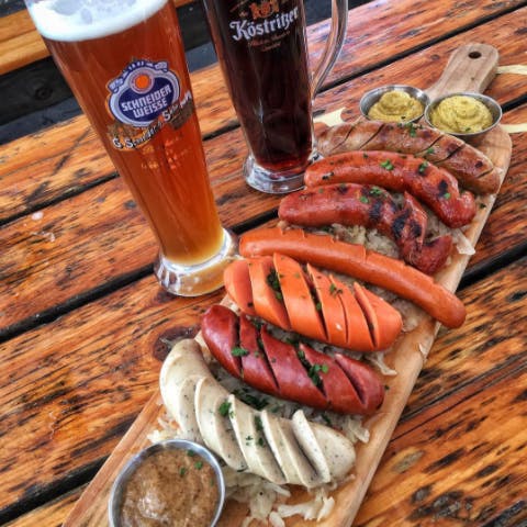 a bottle of beer on a wooden table topped with lots of food