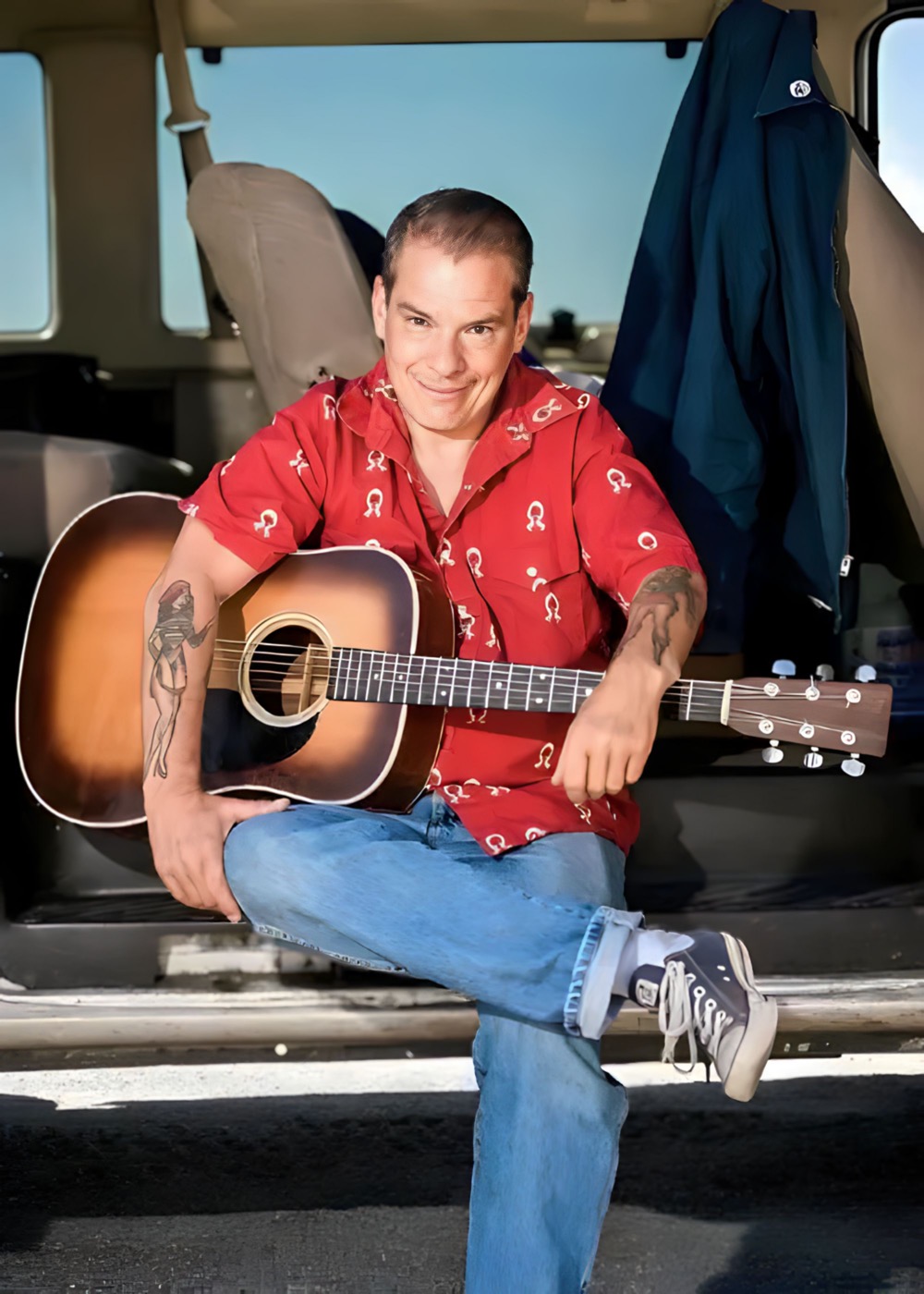 Wayne Hancock sitting on a bench next to a guitar