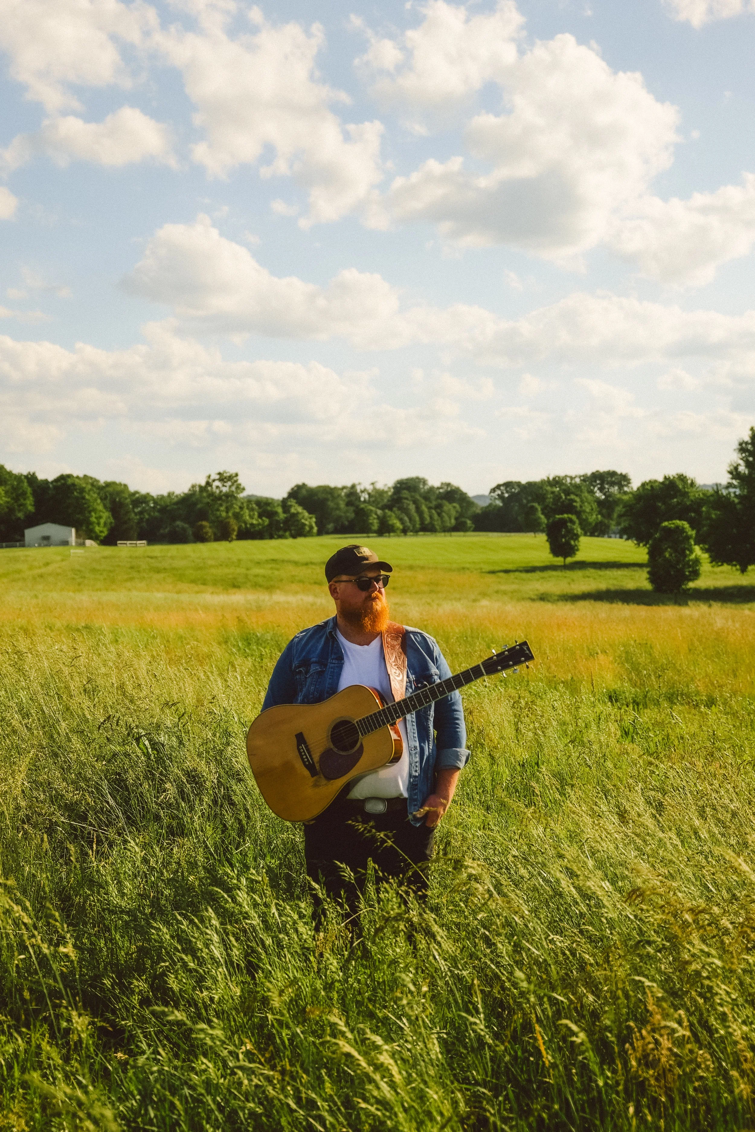 a man holding a guitar in a field